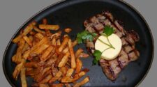 Ein Sirloin-Steak mit Knoblauchbutter und Pommes frites